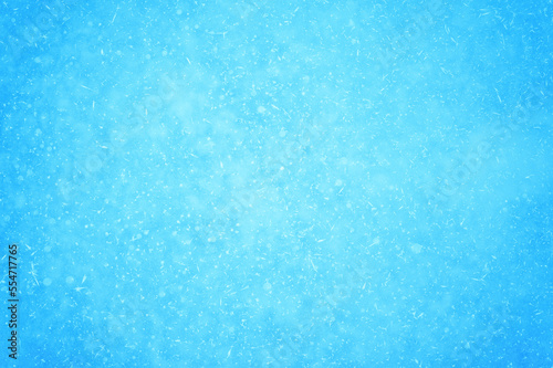 Blue ice interspersed with snowflakes and white frost in a natural light haze. Background