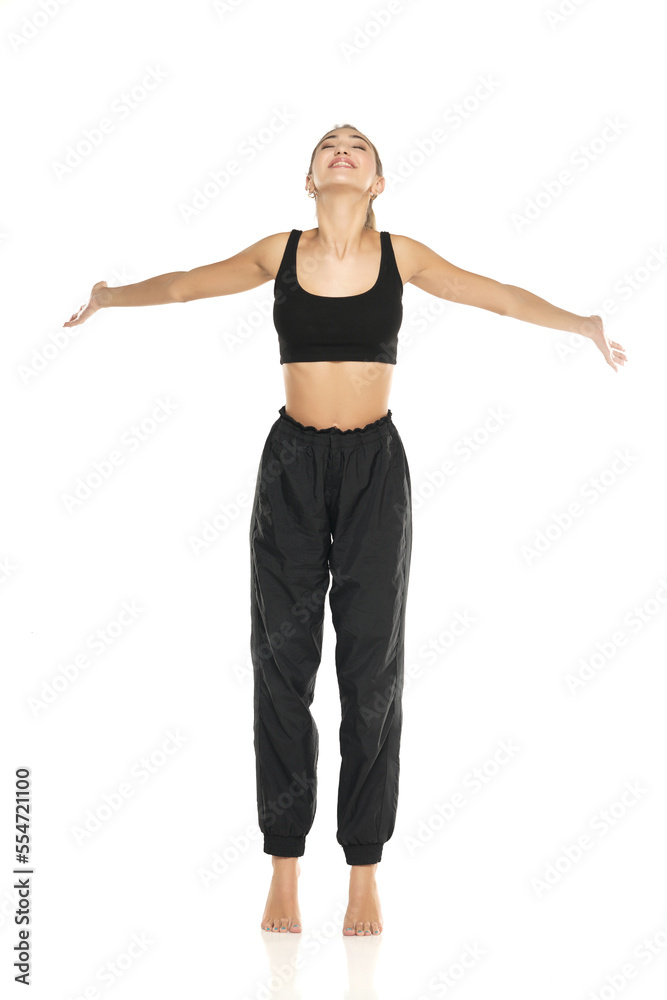 a young barefeet happy woman in black sweatpants and a tank top on a white background a young barefeet happy woman in black sweatpants and a tank top on a white background