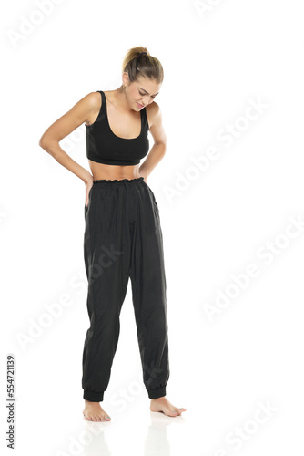 a young sporty woman with pain in her waist on a white background