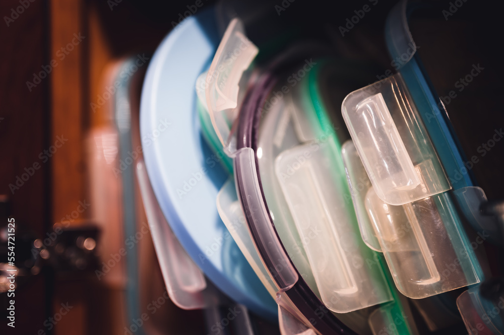 Narrow depth of field picture of an open kitchen cabinet with an assortment of containers and mismatched lids stacked. Narrow depth of field picture of an open kitchen cabinet with an assortment of containers and mismatched lids stacked.