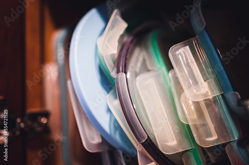 Narrow depth of field picture of an open kitchen cabinet with an assortment of containers and mismatched lids stacked.