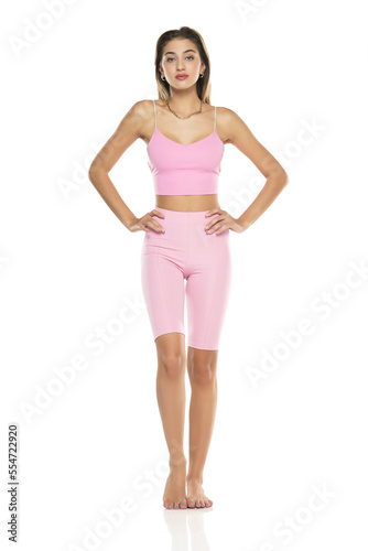 a young barefeet woman in pink short leggings and top posing on a white background © vladimirfloyd