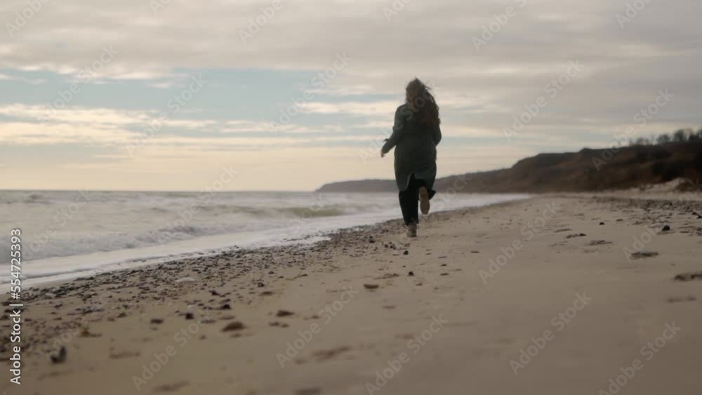 Happy mixed ethnic woman running away on sandy sea beach to background bokeh. Playful smiling asian female airy hair blowing in wind. Low angle wide dreamy cinematic slow motion 120 fps. Happy mixed ethnic woman running away on sandy sea beach to background bokeh. Playful smiling asian female airy hair blowing in wind. Low angle wide dreamy cinematic slow motion 120 fps.