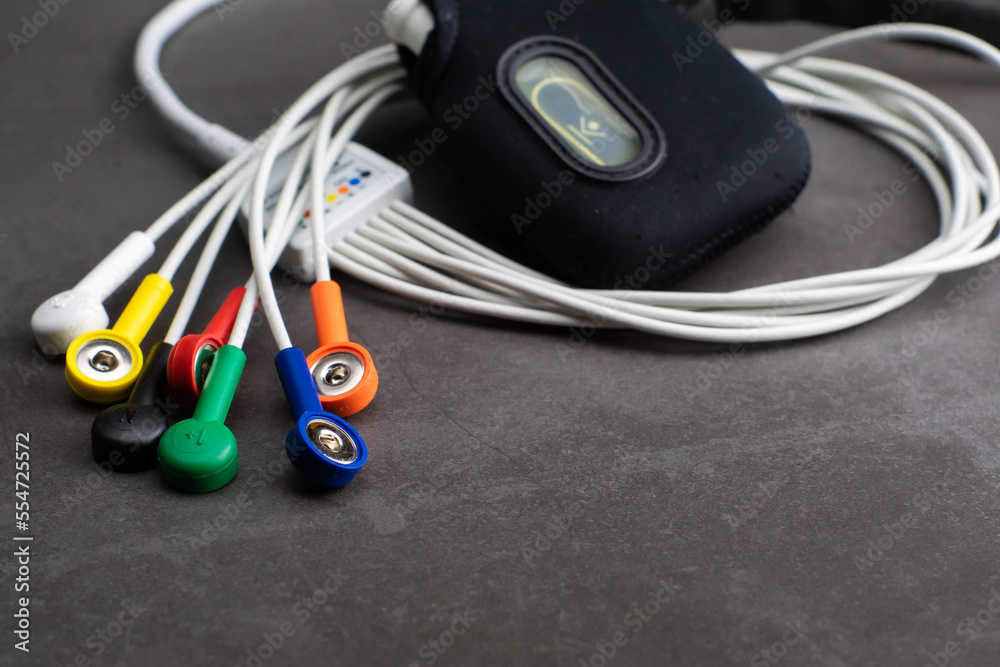 Holter, a medical device for a heart rate measurement with all the colorful cables on industrial gray background