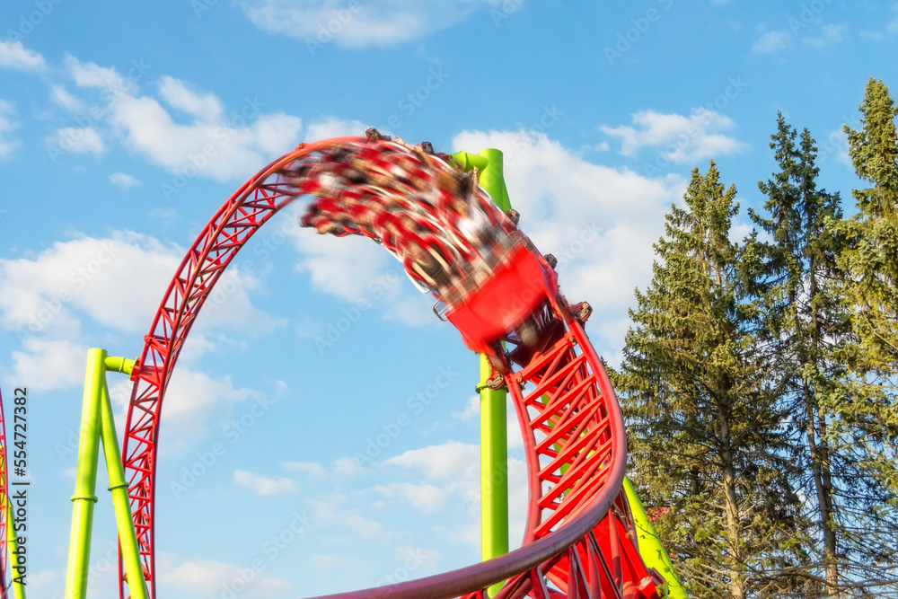 Amusement cart makes circular loops upside down and turns sharply out of the loop with motion blur effect, a roller coaster.
