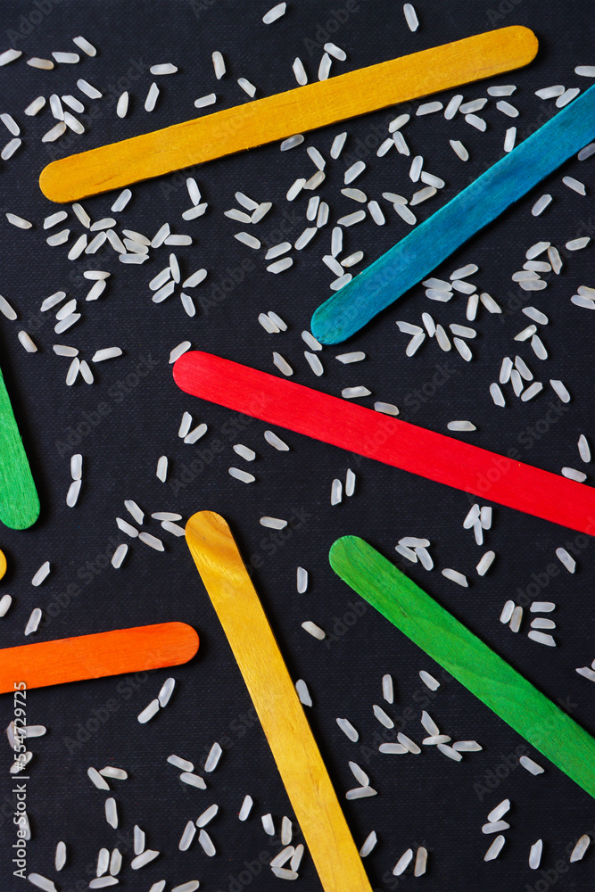 colorful wooden ice cream stick on dark blue background. a pile of the wooden sticks with white rice. abstract wallpaper colorful wooden ice cream stick on dark blue background. a pile of the wooden sticks with white rice. abstract wallpaper