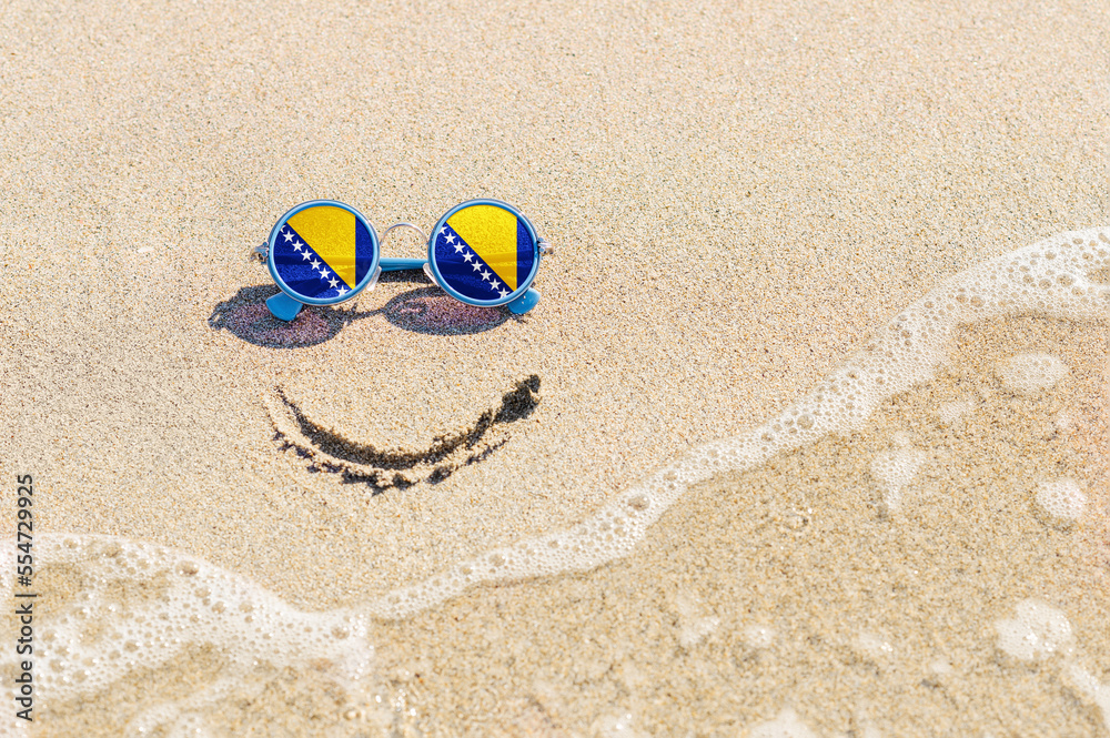Naklejka premium A painted smile on the beach and sunglasses with the flag of Bosnia and Herzegovina.