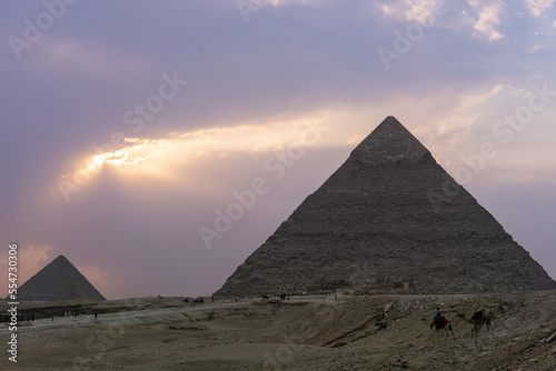 Sunset at the pyramids of Giza  Pyramid of Kefren in the foreground and Pyramid of Menkaure at the end of the shot  purple sky with clouds.