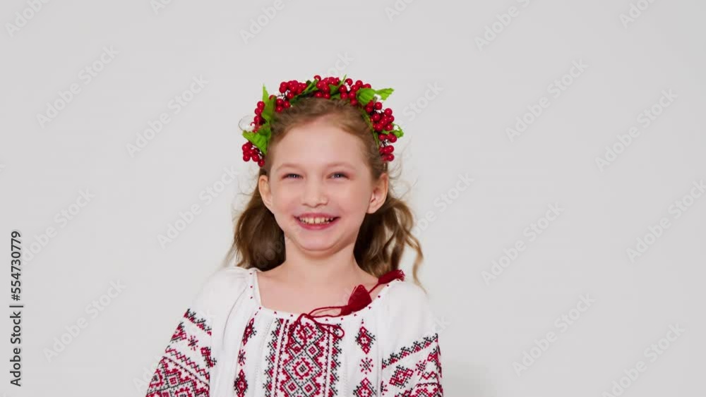 Playful woman smiling, flirting in front of the camera on a white studio background. A cute little girl in a Ukrainian vyshyvanka. Playful woman smiling, flirting in front of the camera on a white studio background. A cute little girl in a Ukrainian vyshyvanka.