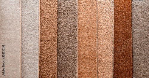 Variety of carpets and carpets of different colors on the stand in the store or the factory. Multicolored carpet samples