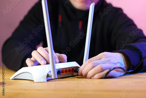 connecting internet cable to router with antennas on table