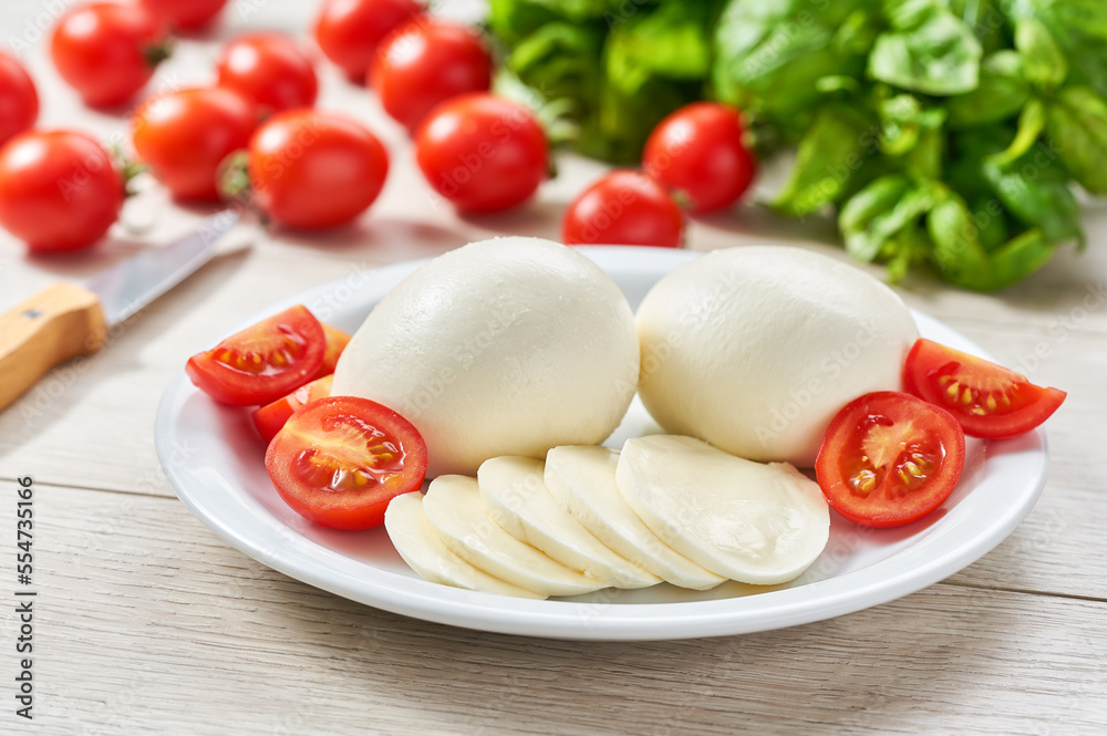 traditional italian mozzarella Buffalo cheese with cherry tomatoes and green fresh organic basil, ingredients for Caprese salad.