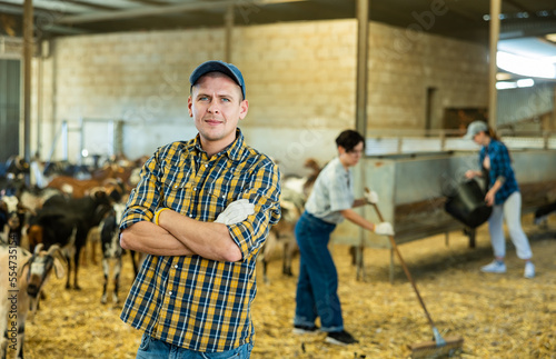 Portrait of confident man professional goat breeder in stall on goat farm