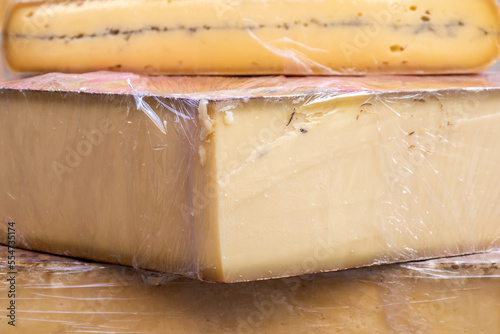 closeup of several large portions of cheese wrapped in cling film. food preservation