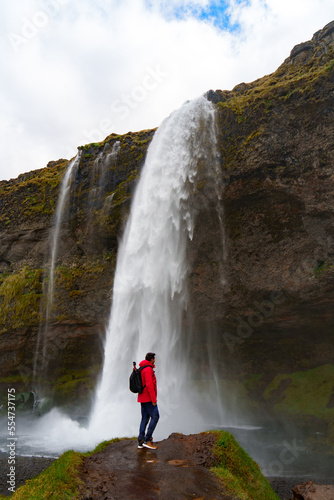 happy man enjoying nature in iceland with a waterfall in the background