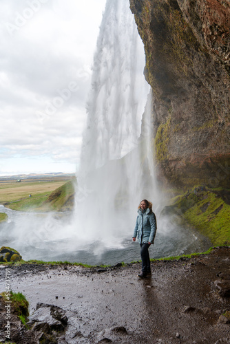 happy woman enjoying nature in iceland with a waterfall in the background