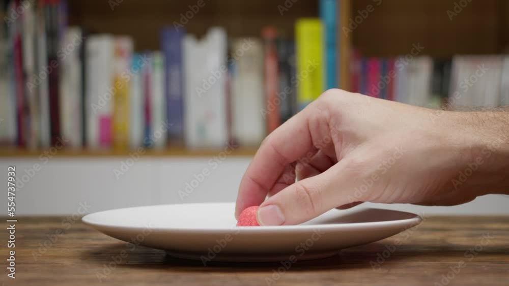 Une personne prend le dernier bonbon fraise dans un plat