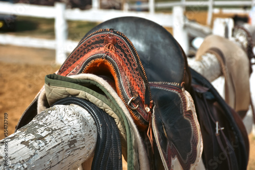 Traditional nomad horse saddle and rider equipments in the horse farm hanging on white fences waiting to be used