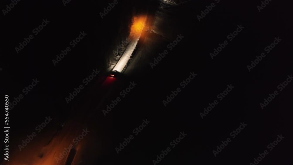 Night aerial video of car slow driving on winter road in winter snowy forest, side view Night aerial video of car slow driving on winter road in winter snowy forest, side view