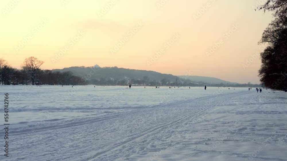 Sunset on a frosty winter evening over a snow-covered field, where the townspeople go skiing, walking their dogs. Active recreation in winter, winter sports, big snowy field in Krakow on Christmas Eve Sunset on a frosty winter evening over a snow-covered field, where the townspeople go skiing, walking their dogs. Active recreation in winter, winter sports, big snowy field in Krakow on Christmas Eve