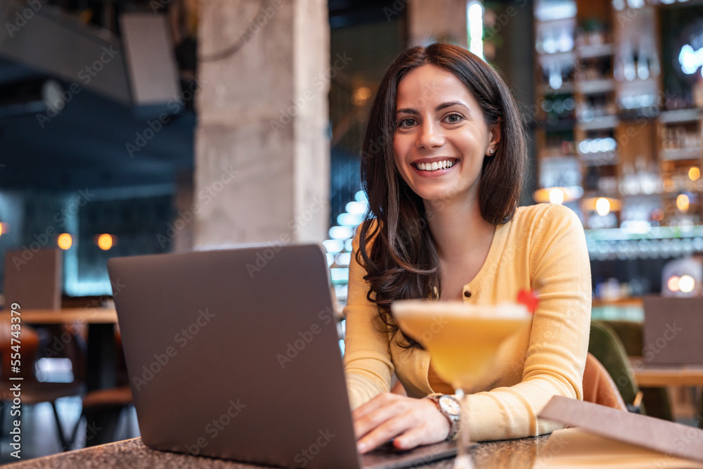 Portrait of young woman using laptop at cafe
