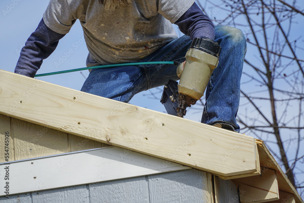 handyman using nail gun to install shingle to repair roof handyman using nail gun to install shingle to repair roof