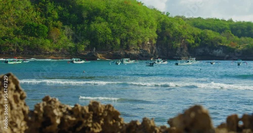 Wallpaper Mural Early morning on Crystal Bay Beach with silhouettes of fishing boats on the ocean. Relax view of green tropical paradise Nusa Penida island. Rocky coastline. Cloudy weather. Torontodigital.ca