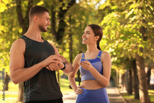 Attractive happy couple checking pulse after training in park on sunny day