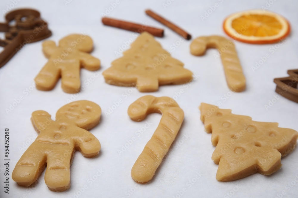 Unbaked biscuits and cookie cutters on light table, closeup