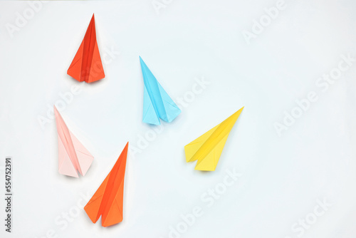 Handmade colorful paper planes on white table, flat lay. Space for text