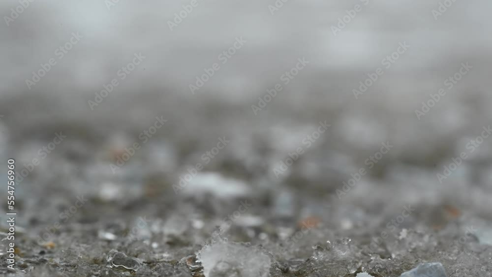 macro ground level closeup view of rock salt ice-melt on concrete with snow macro ground level closeup view of rock salt ice-melt on concrete with snow