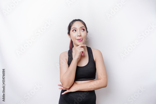 A sporty Asian woman is hungry and touching her belly while looking aside thinking what to eat © Reezky