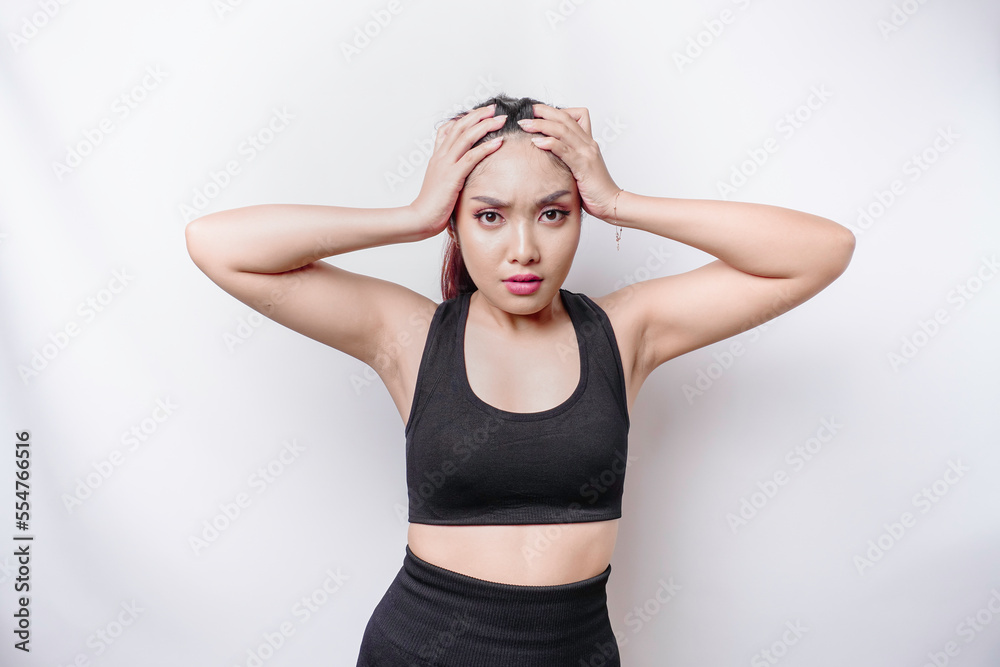 A portrait of an sporty Asian woman wearing a sportswear isolated by white background looks depressed