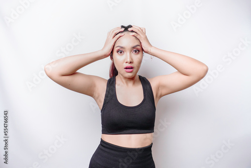 A portrait of an sporty Asian woman wearing a sportswear isolated by white background looks depressed
