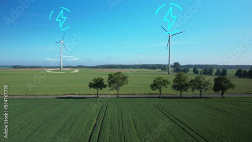 Aerial view of wind turbine producing energy on rural field with road during sunny day - Digital motion graphic power symbol in blue color - Futuristic concept photo