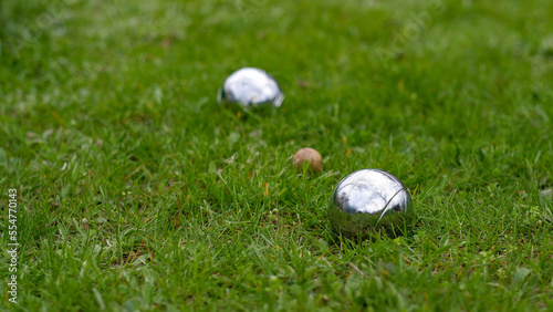 Close-up of steel petanque balls on a green lawn. Selective focus. Petanque balls made of chrome-plated steel lie on the grass.