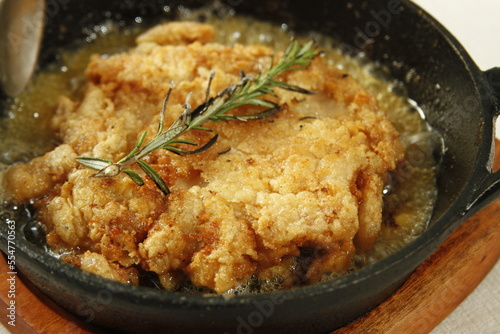 Tuscan style chicken sizzling in butter with rosemary in a skillet