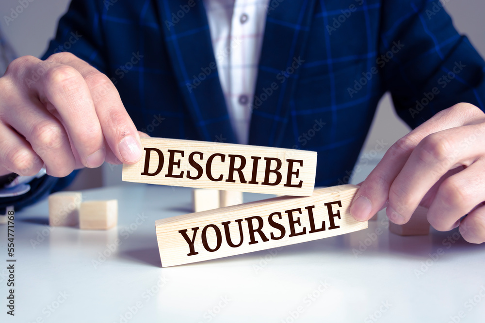 Obraz premium Closeup on businessman holding a wooden block with DESCRIBE YOURSELF message