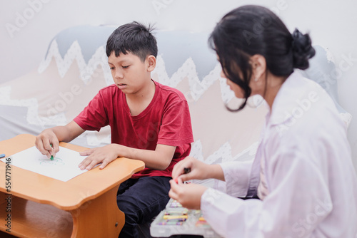 A professional child education therapist during theraphy session with a kid in a family support center.