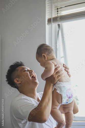 Excited father lift up cute baby boy at home