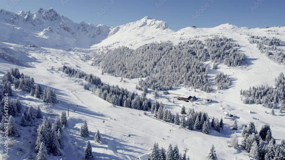 Ski track with skiers descending with lift left at Courchevel France, Aerial pan left reveal shot Ski track with skiers descending with lift left at Courchevel France, Aerial pan left reveal shot