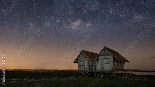 Close up time lapse of milky way and stars above the abandoned twin house near the lake with clear night sky photo