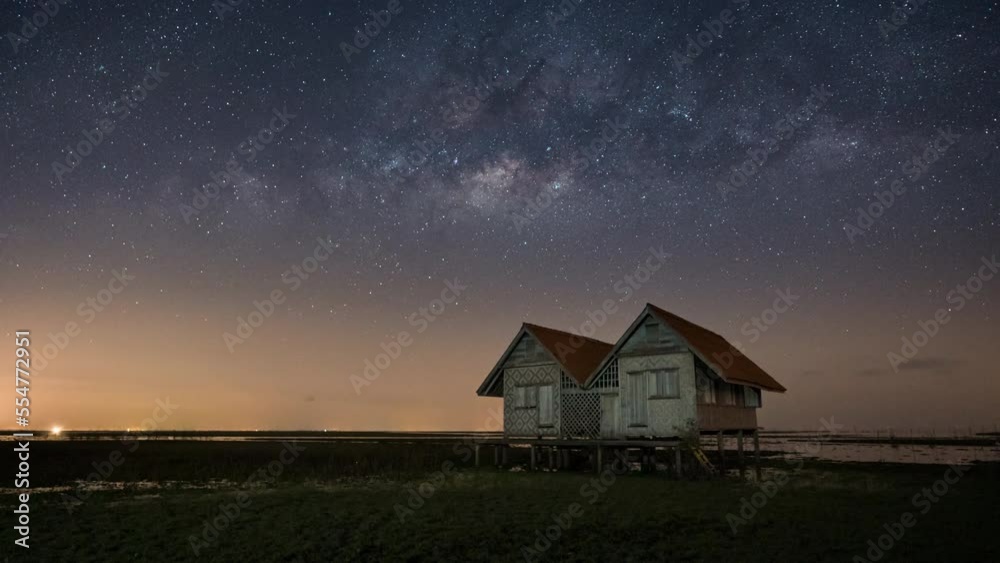 Zoom out time lapse of milky way and stars above the abandoned twin house near the lake with clear night sky Zoom out time lapse of milky way and stars above the abandoned twin house near the lake with clear night sky