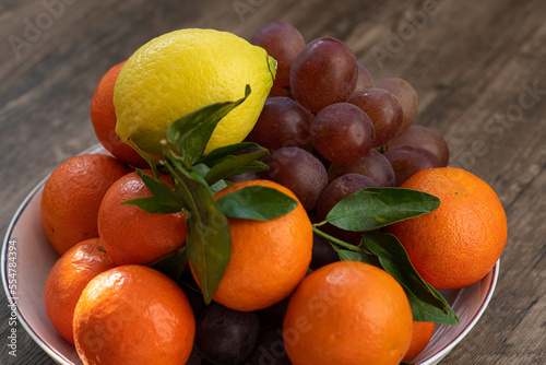 Ripe fruits  lemon  grape  orange on a white plate. Citrus fruits on a platter. Still-life. on a wooden background. top view. close-up.