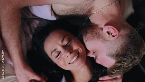 A man and a woman are resting together with their heads pressed against each other. The camera shoots from above