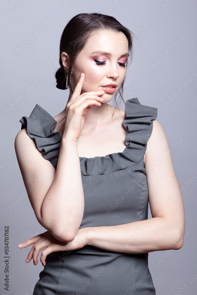 Portrait of young woman in gray dress on grеy background. Portrait of young woman in gray dress on grеy background.