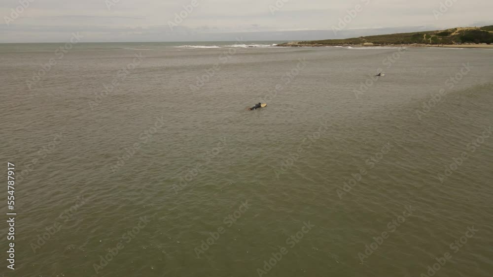 Surfer lying on board and paddling, waiting for prefect waves of ocean - Uruguay,South America - aerial drone shot Surfer lying on board and paddling, waiting for prefect waves of ocean - Uruguay,South America - aerial drone shot