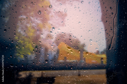 Water droplets clinging to the window overlooking a faint view outside
