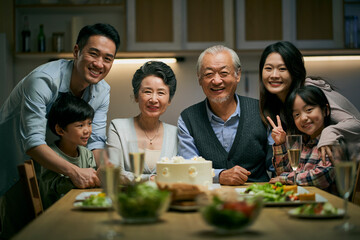 senior asian couple celebrating wedding annversary with three generational family