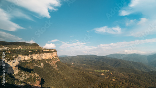 Clouds across blue daytime sky in a mountain green valley. Shadow from clouds on rocks and hills. Aerial view of nature